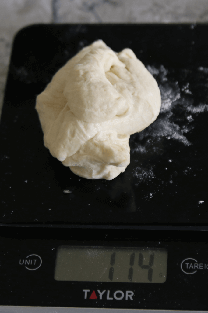 sourdough hamburger buns being measured on kitchen scale