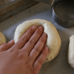 soft sourdough hamburger bun dough being pressed down