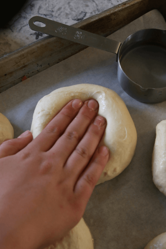 soft sourdough hamburger bun dough being pressed down