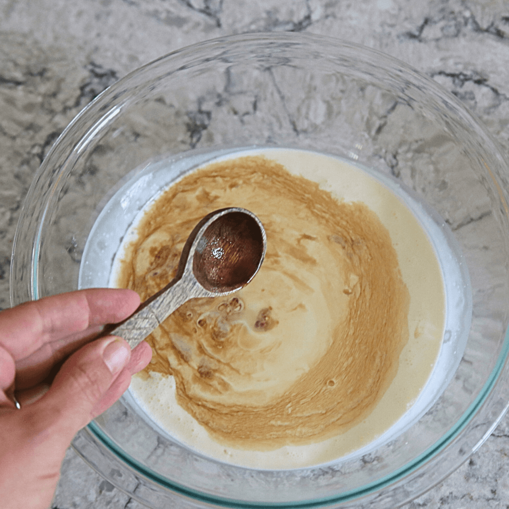 Whipped Cream with vanilla extract being added to bowl