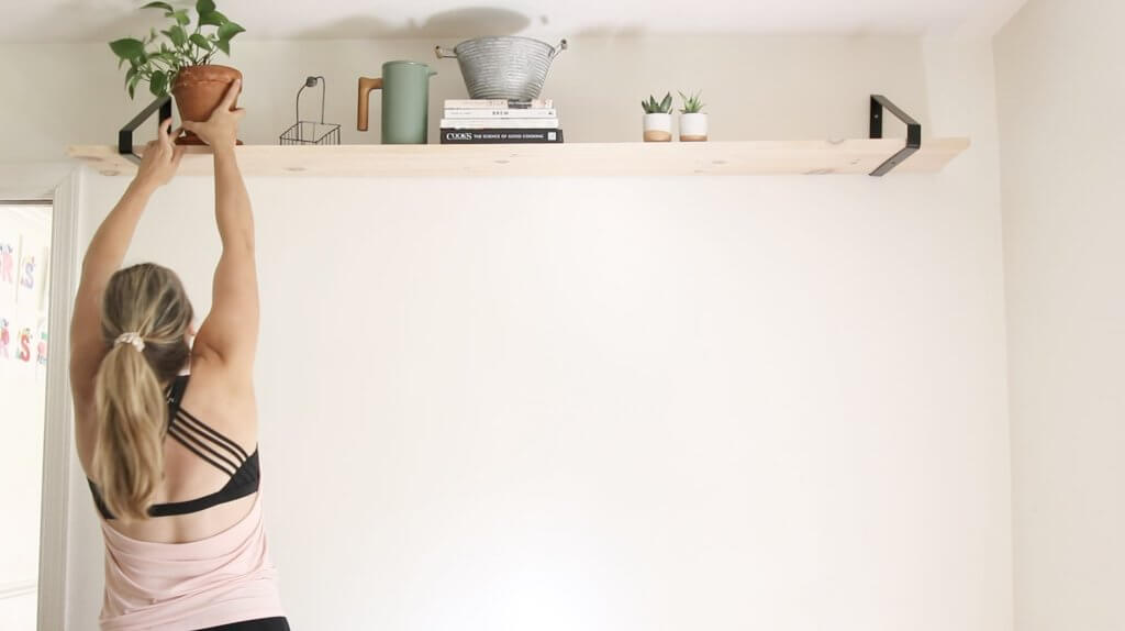 Woman putting freshly watered plants on a shelf