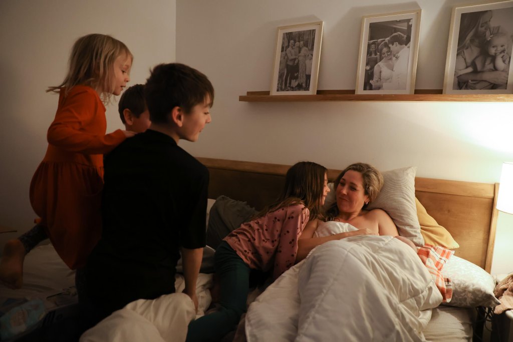 Woman in bed with new baby surrounded by her other children
