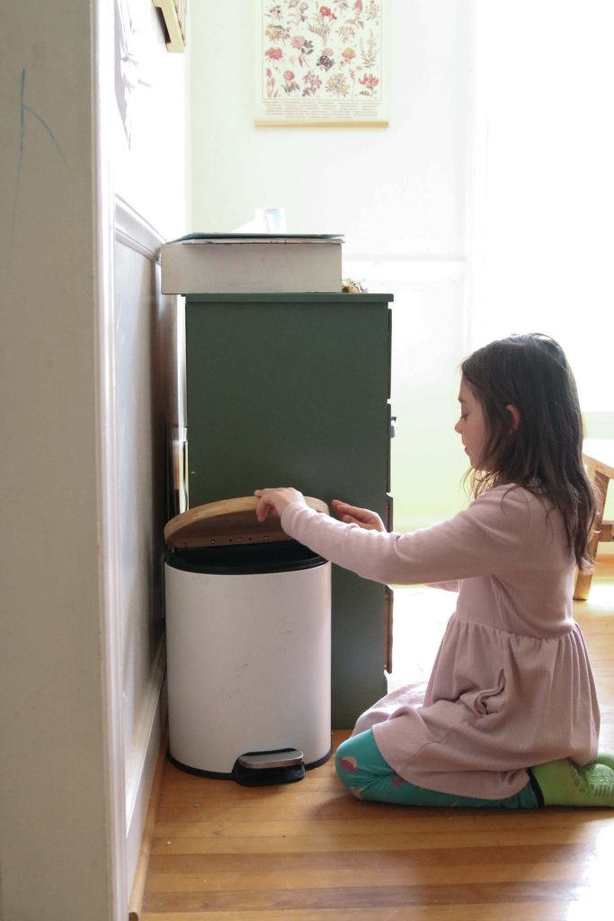 Little girl next to trash can