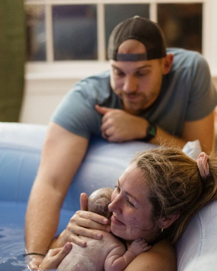 Woman holding her newborn baby in birth tub