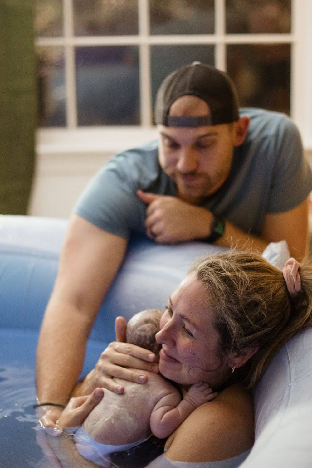 Woman holding her newborn baby in birth tub
